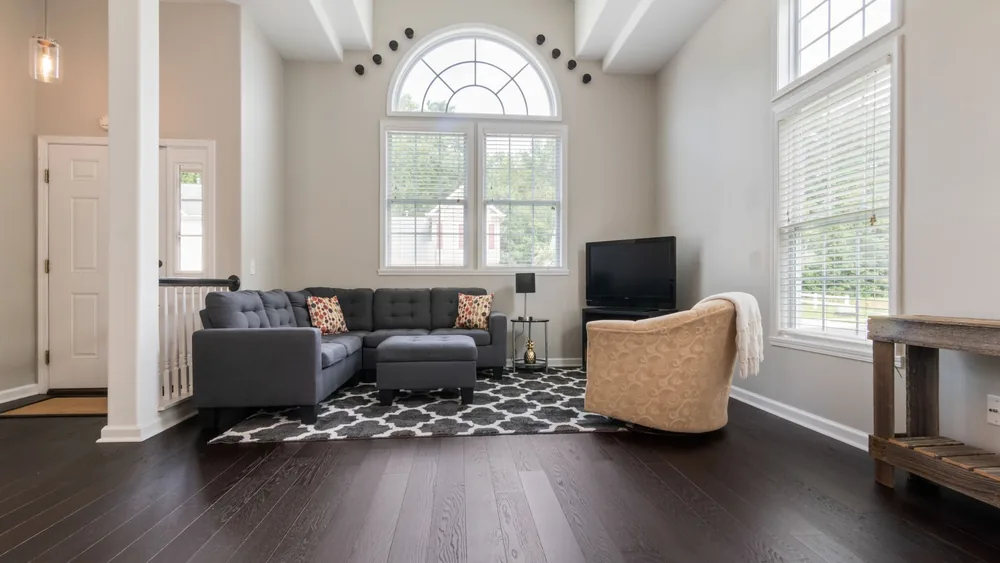 Bright living room with modern furniture, high ceilings, and big windows.