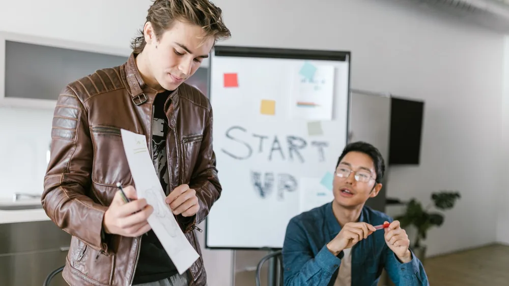 Two young men collaborating in a startup meeting with brainstorming session.