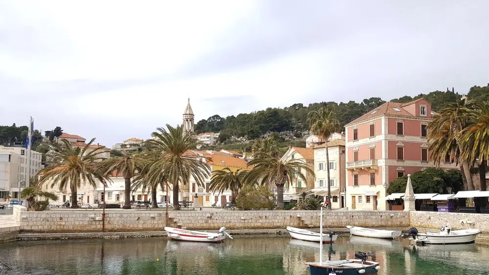 Beautiful harbor in Hvar with boats, historic buildings, and palm trees. A charming travel destination.