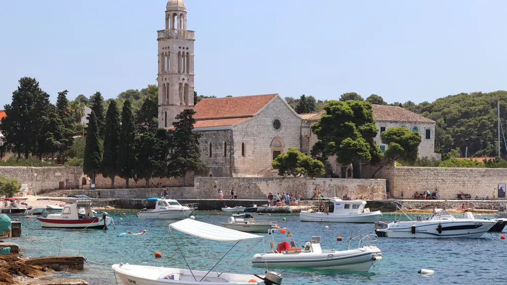 A serene coastal town featuring a historic church, moored boats, and clear blue waters.