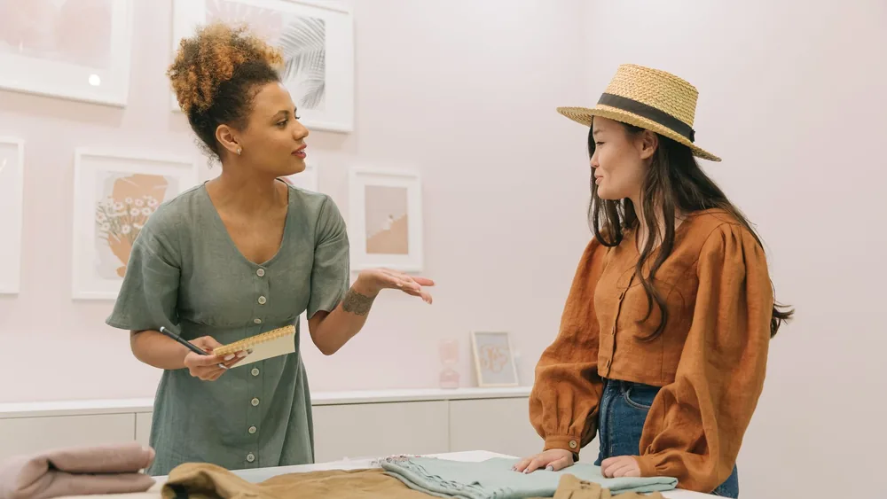 Two women fashion designers discussing and planning together in a stylish indoor setting