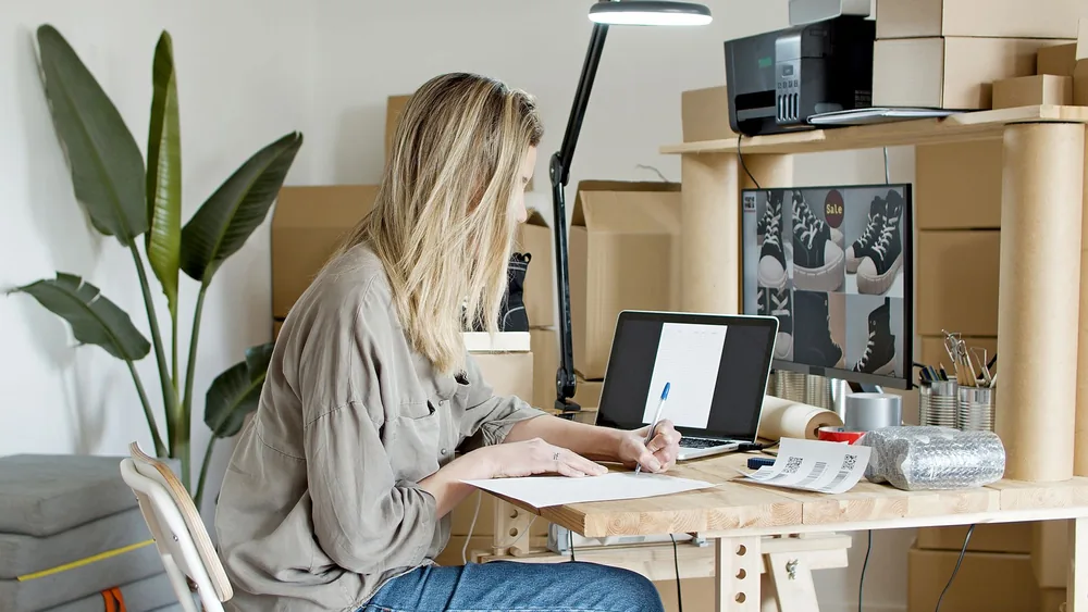 A young woman managing her online store startup, working diligently from her home office in Portugal.