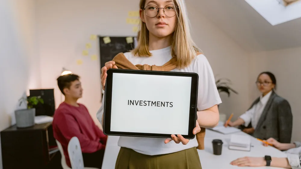 Young professional holding tablet in team meeting focused on investments.