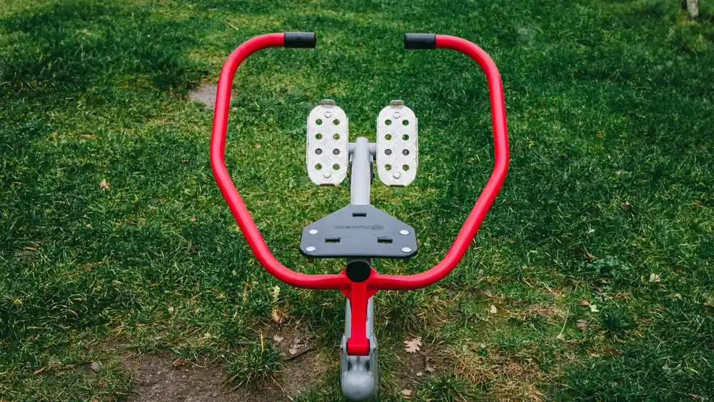 A vibrant red exercise device in a Polish park's green outdoor setting.