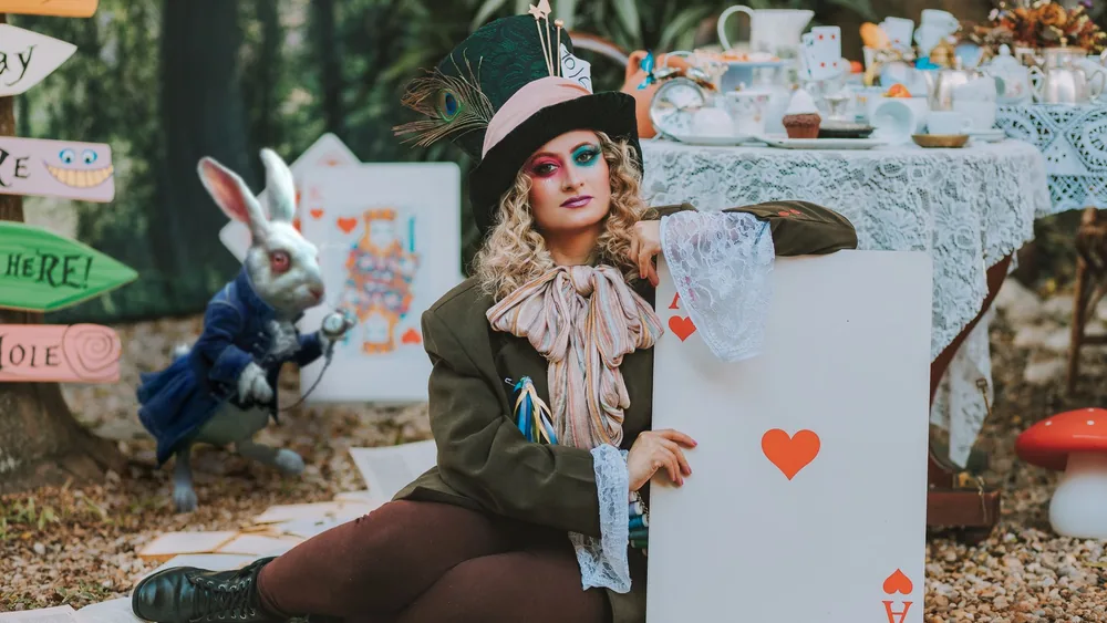 A whimsical portrait of a person dressed as the Mad Hatter, surrounded by Wonderland-themed decor.