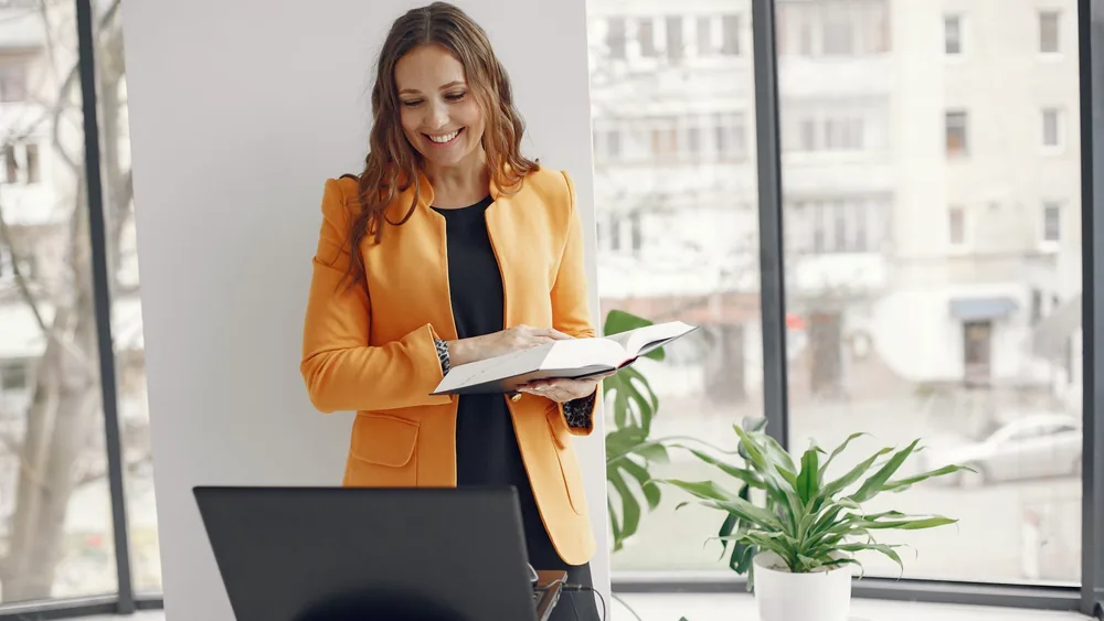 Confident businesswoman working on laptop in stylish office with natural light. Ideal for business themes.