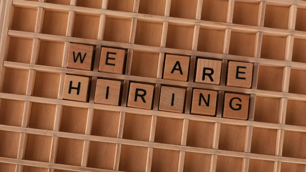 Wooden tiles on a board forming the phrase 'We Are Hiring', ideal for job announcements.