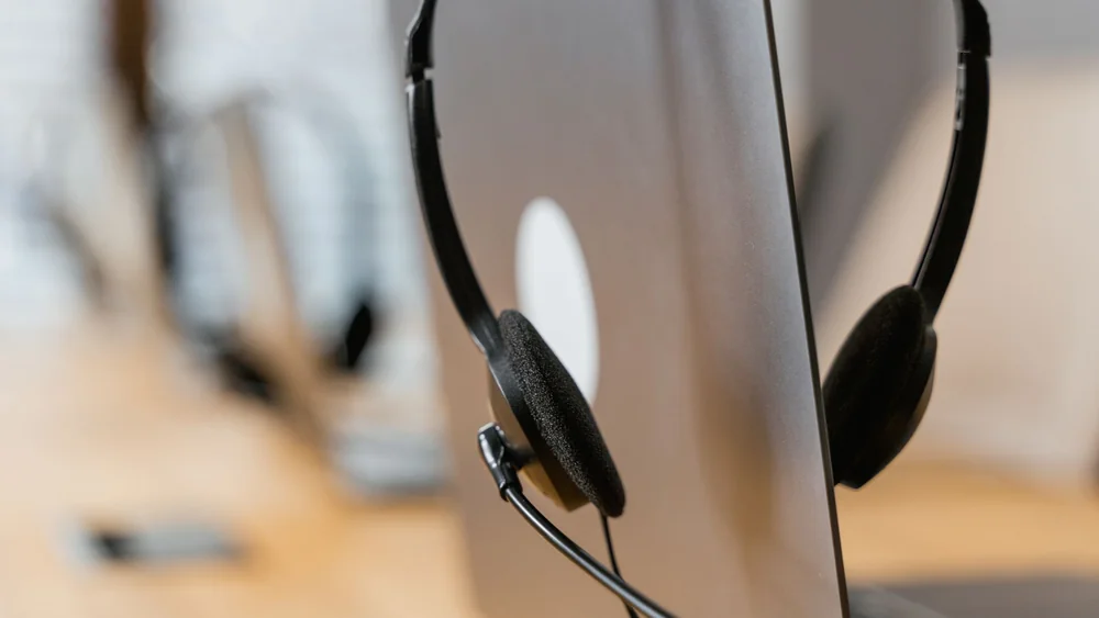 A headset on a desk, the core kit of a customer care role