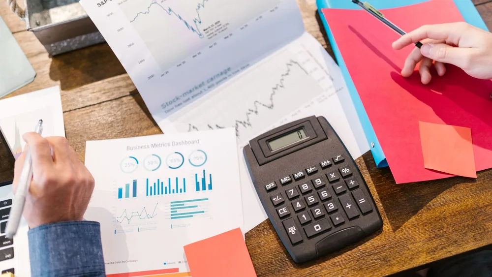 Financial analysis and planning tools with graphs and calculator on a table.