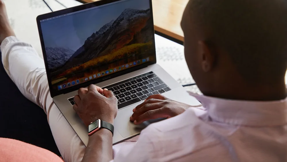 Back view of  anonymous African American businessman watching laptop while working on project