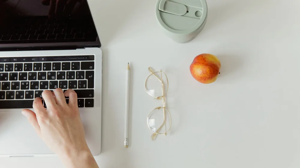 Simple minimalist workspace with a laptop, coffee cup, and apple. Ideal for office theme.