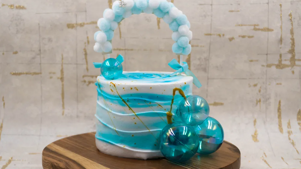A beautifully crafted blue and white cake with decorative spheres, perfect for celebrations.