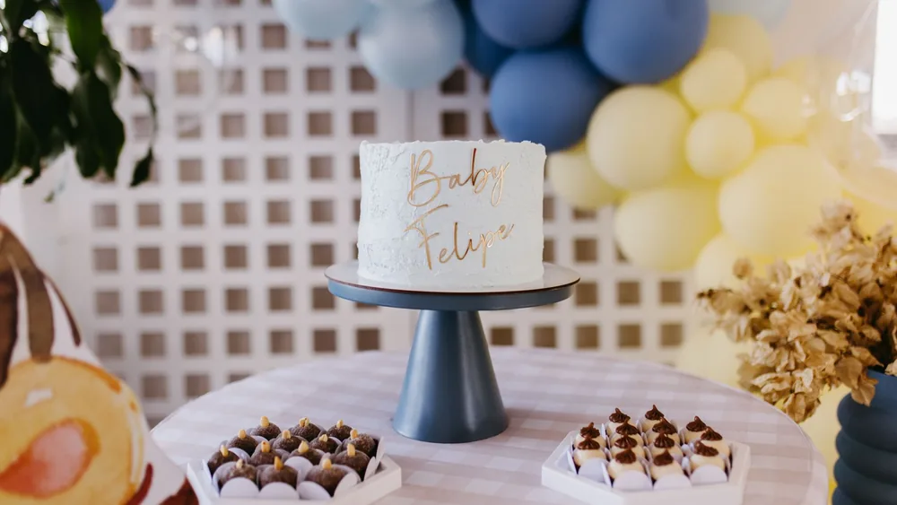 Baby shower setup with personalized cake and decorations in soft tones.