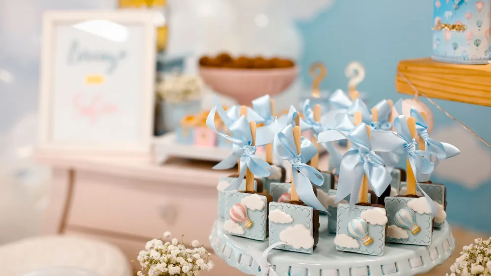 Elegant baby shower dessert table with pastel decorations and sweet treats.