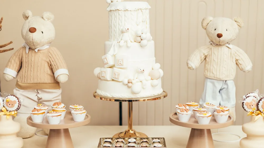 Adorable teddy bear themed baby party setup with cake, cupcakes, and plush toys.