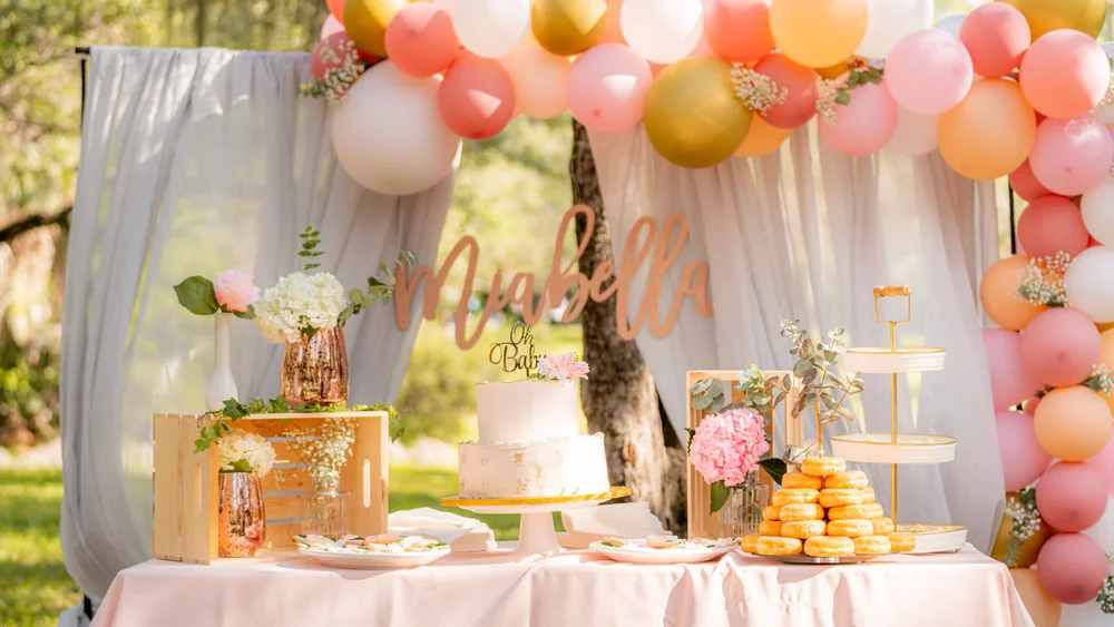 Elegant baby shower dessert table with pastel decorations and sweet treats.