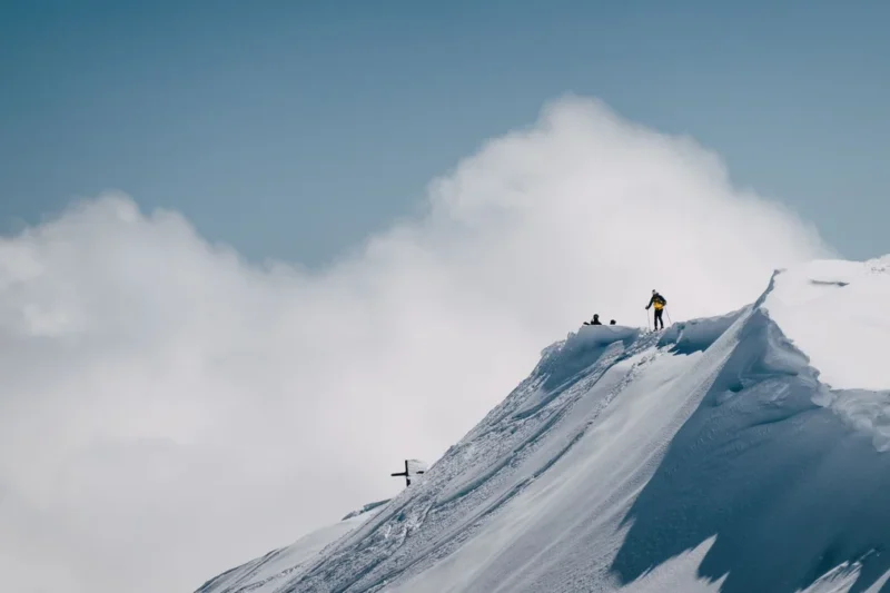 A climber on a snow ridge near a summit