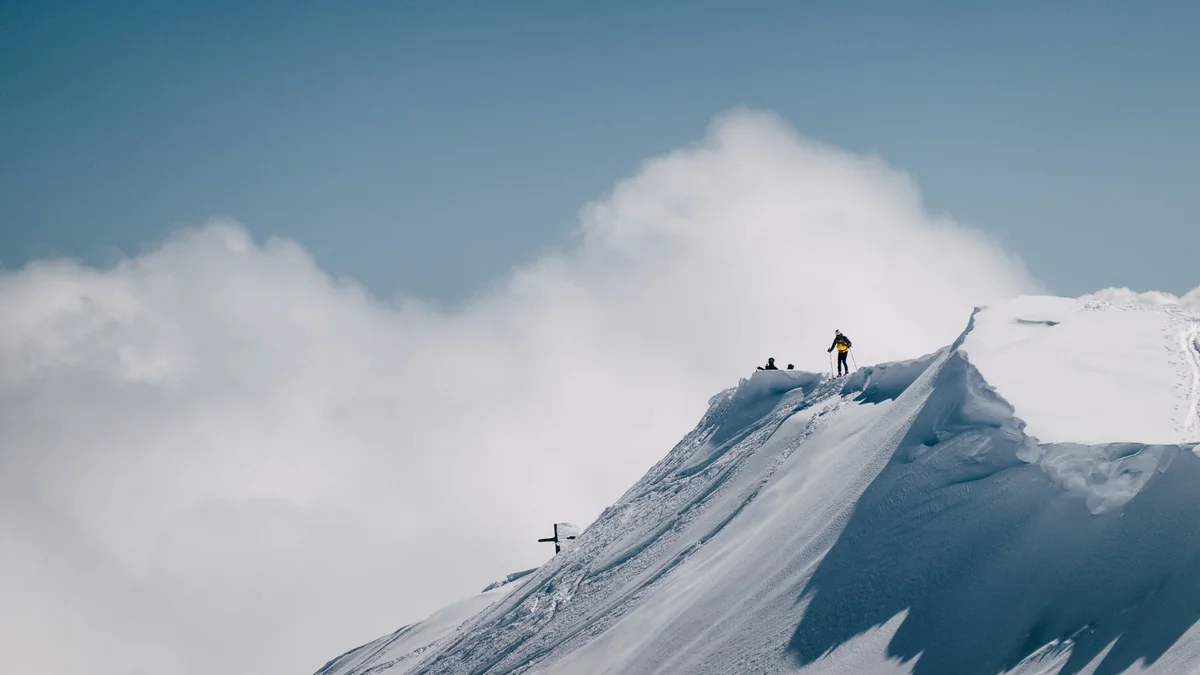 A climber on a snow ridge near a summit