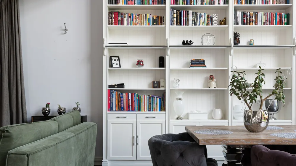 Elegant modern living room with bookcase, plush sofa, and decorative plants.