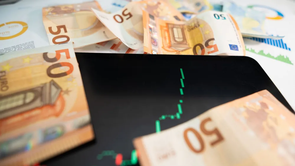 Close-up of 50 euro banknotes with a digital stock market chart on a tablet, depicting financial growth.
