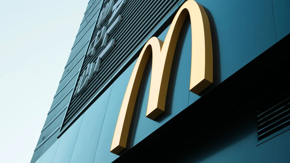 Large fast food restaurant golden arch sign on a modern building facade.