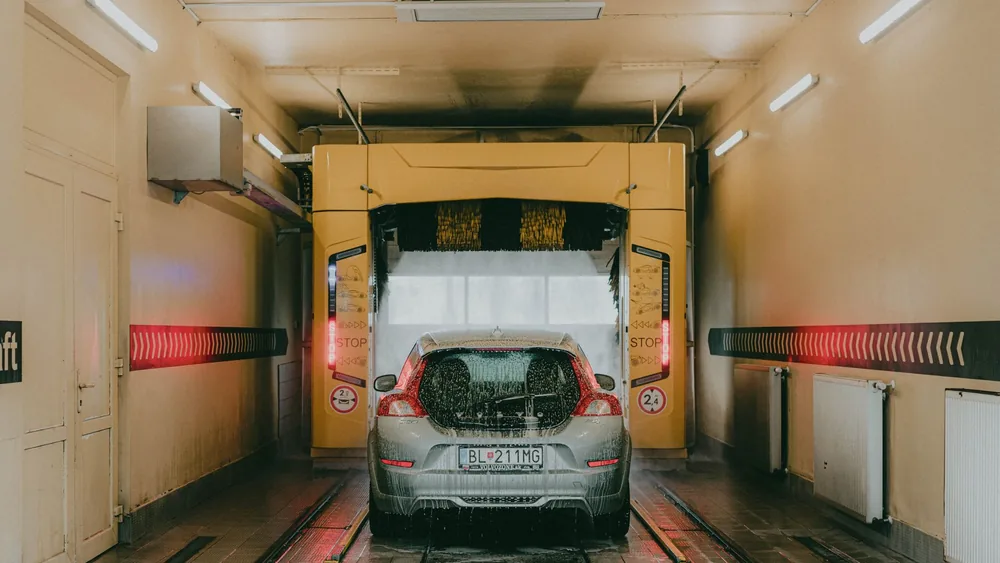 A modern car undergoing an automated interior car wash with bright lights and soapy water.
