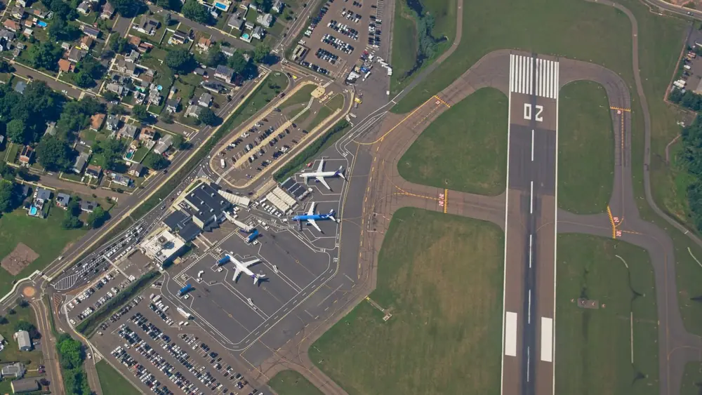 Aerial shot of an airport in New York, showcasing runways, planes, and nearby neighborhoods.