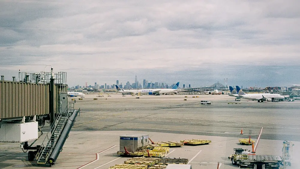 Aircraft waiting on JFK airport apron with New York City skyline in the background.