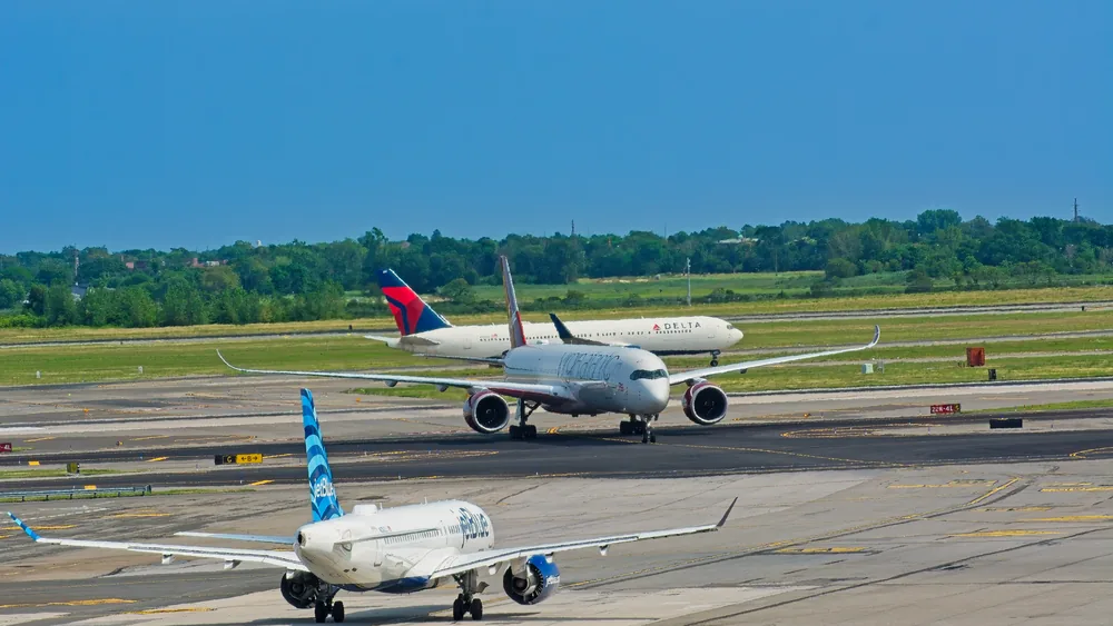 Airplanes from various airlines taxiing on a JFK airport runway in New York.