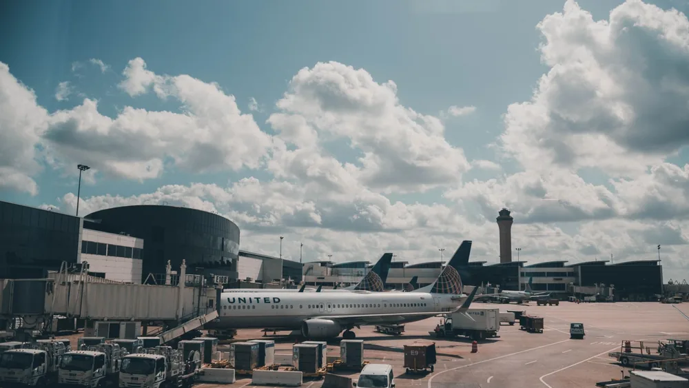 A United airplane parked on the airport apron under a scenic cloudy sky.