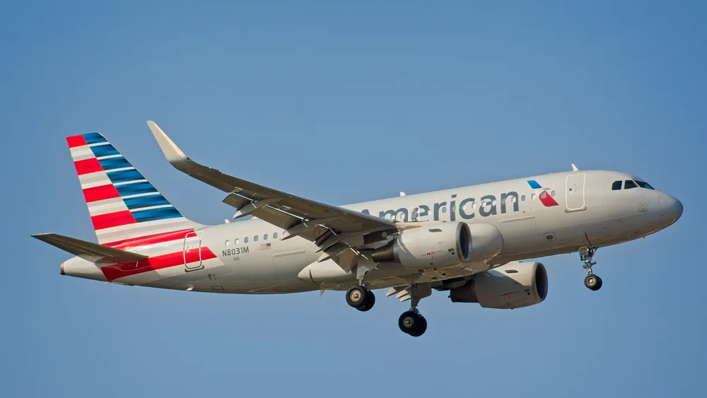 American Airlines Airbus A319 airplane landing under clear sky in New York City.