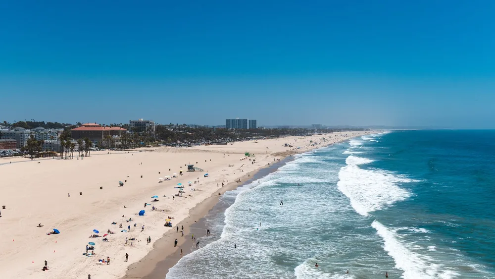 Aerial view of a lively beach scene at Santa Monica, capturing people enjoying the sun and sea.