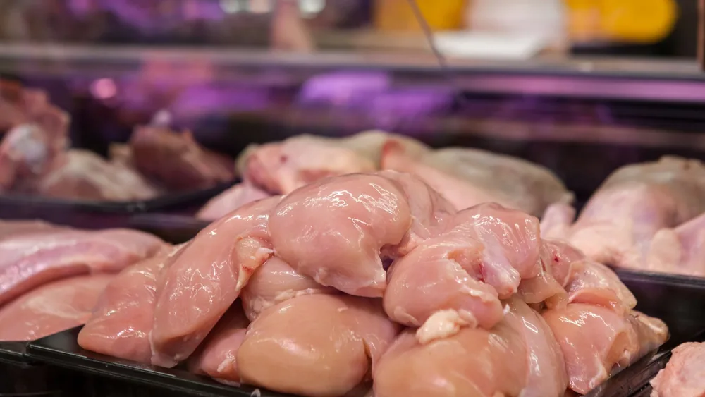 Fresh raw chicken breasts displayed in a supermarket setting, ready for purchase.