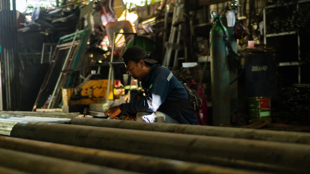 A focused artisan works diligently in a busy industrial workshop, showcasing modern craftsmanship.