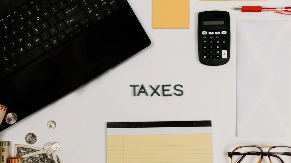 Organized office supplies for managing taxes, featuring a calculator, keyboard, and notepad.