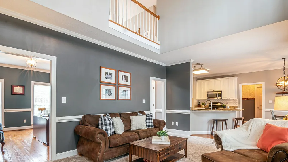 Luxurious living room with brown sofas, coffee table, and open kitchen layout.