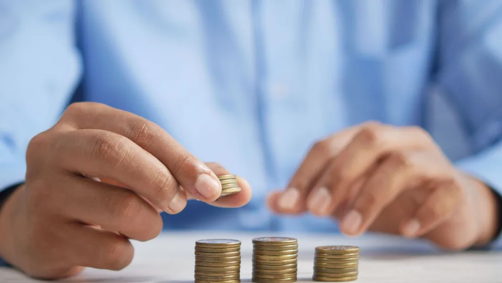 Close-up of hands stacking gold coins, symbolizing financial growth and savings.