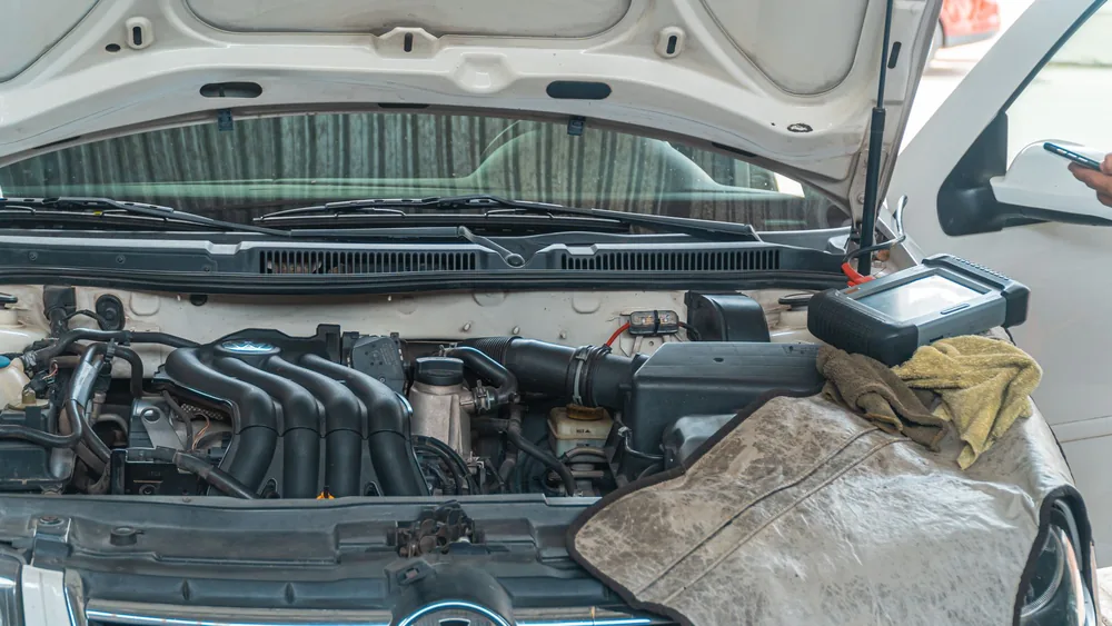 Close-up of a Volkswagen car engine undergoing repair in a garage, tools and diagnostic equipment in use.