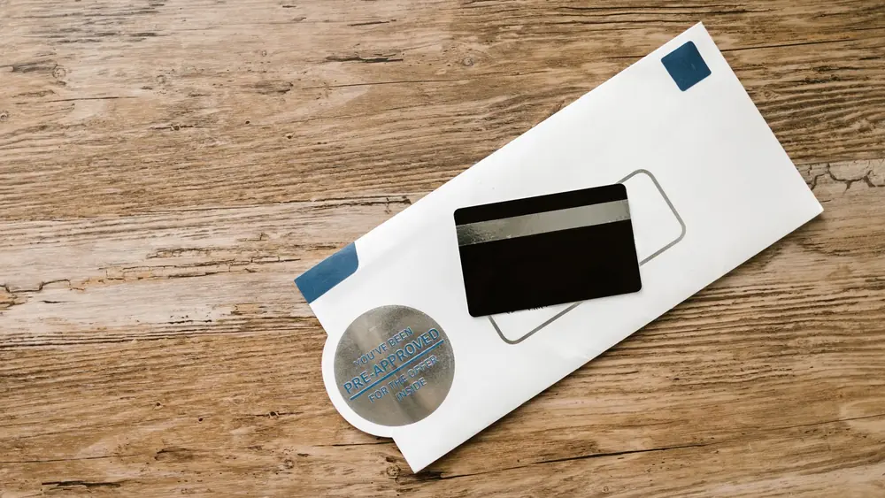 A blank credit card with a pre-approved envelope on a wooden table, showcasing financial opportunities.