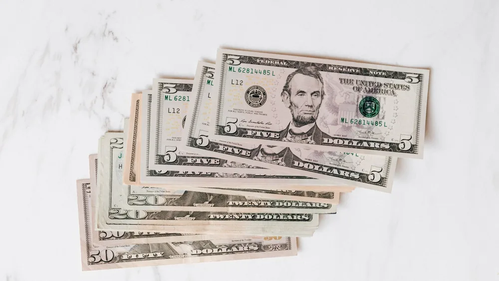 Top view heap of american dollar bills in different denominations placed on marble surface