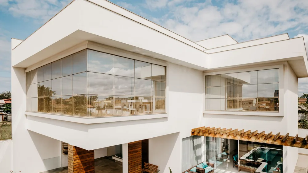 Exterior of contemporary cottage with large windows and stylish terrace against cloudy blue sky