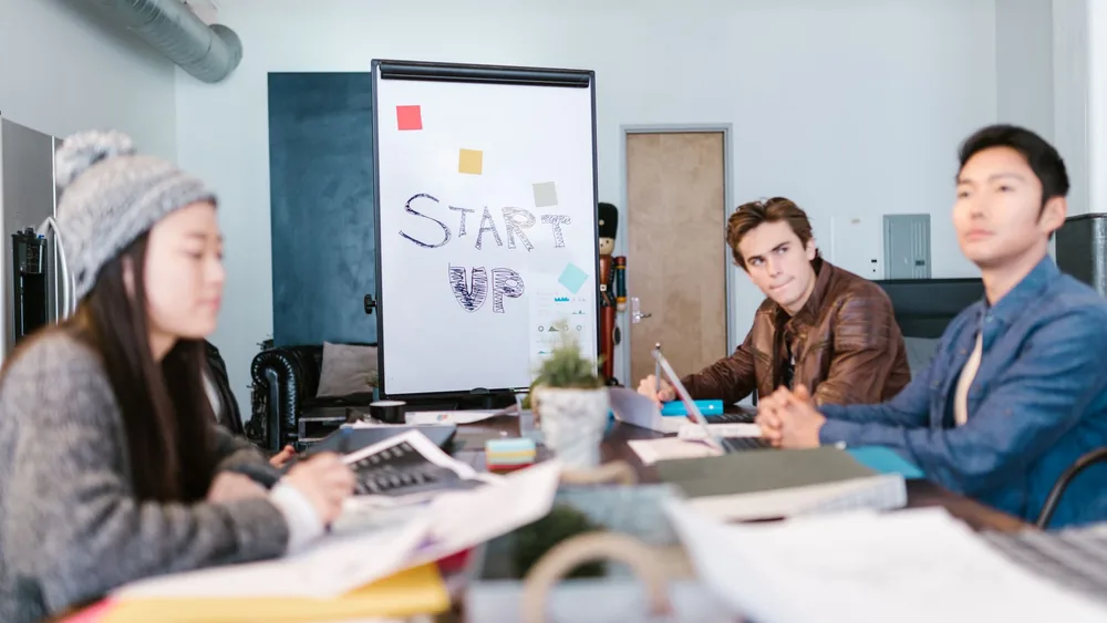 A group of young professionals brainstorming ideas in a startup office setting.