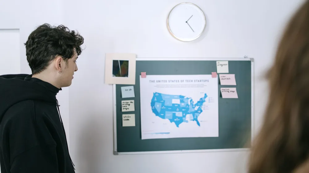 Young professionals discussing a map of US tech startups in a modern office setting.