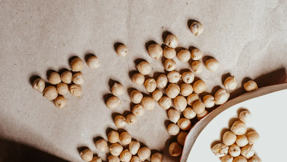 Close-up of dried chickpeas scattered on a textured brown surface, perfect for healthy food imagery.
