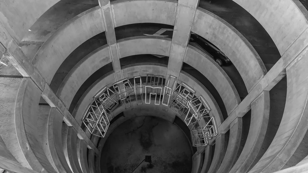 A grayscale view of a spiral concrete parking garage with geometric design elements.