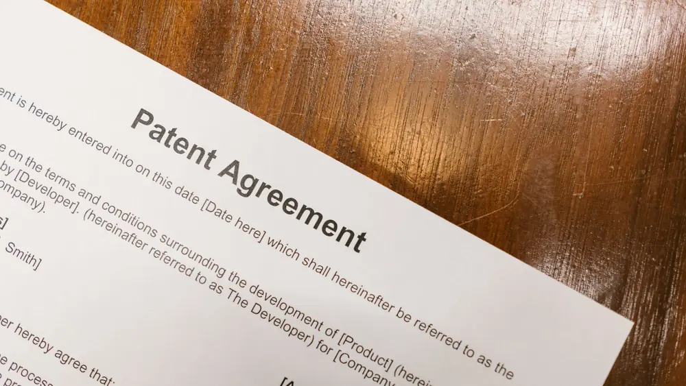 Detailed close-up of a patent agreement document on a polished wooden table.