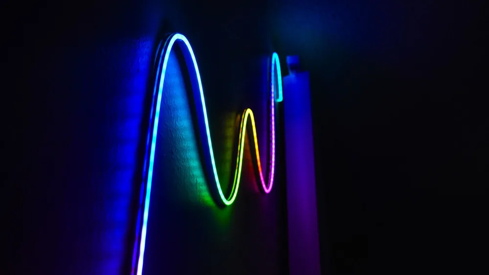 Colorful neon wave pattern LED lights illuminating a dark room for a modern home decor aesthetic.