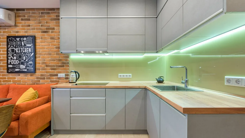 Sleek kitchen with gray cabinets, brick wall, and stylish lighting for a cozy atmosphere.