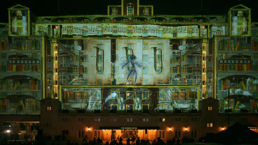 Night projection mapping on The Queens Hotel, Leeds featuring artistic visuals and vibrant lights.