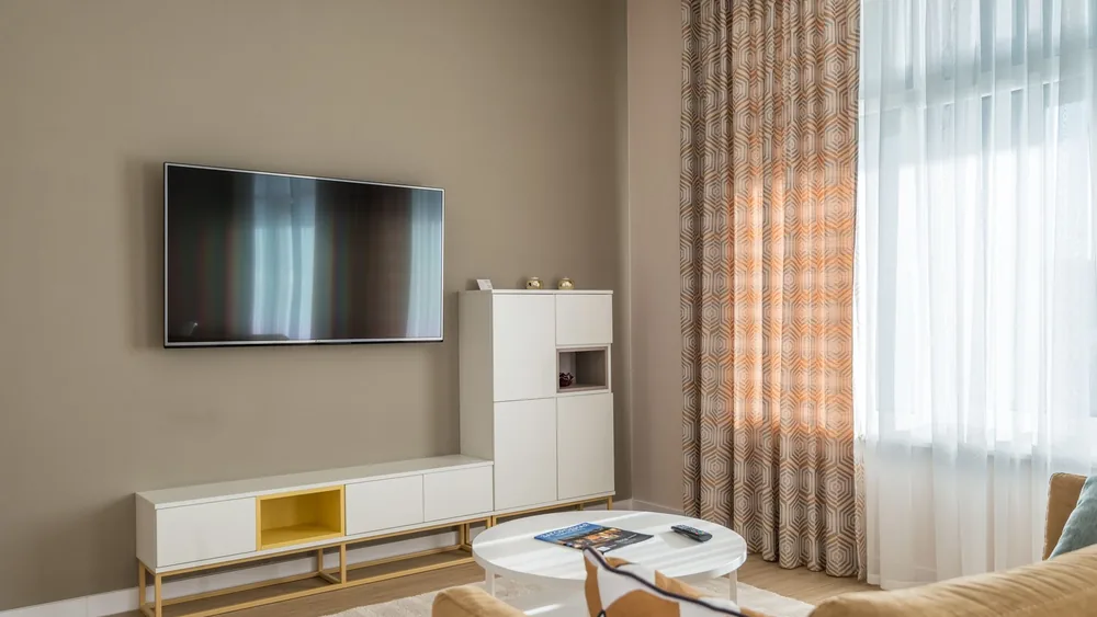 Cozy living room interior with beige walls, flat-screen TV, and stylish decor.